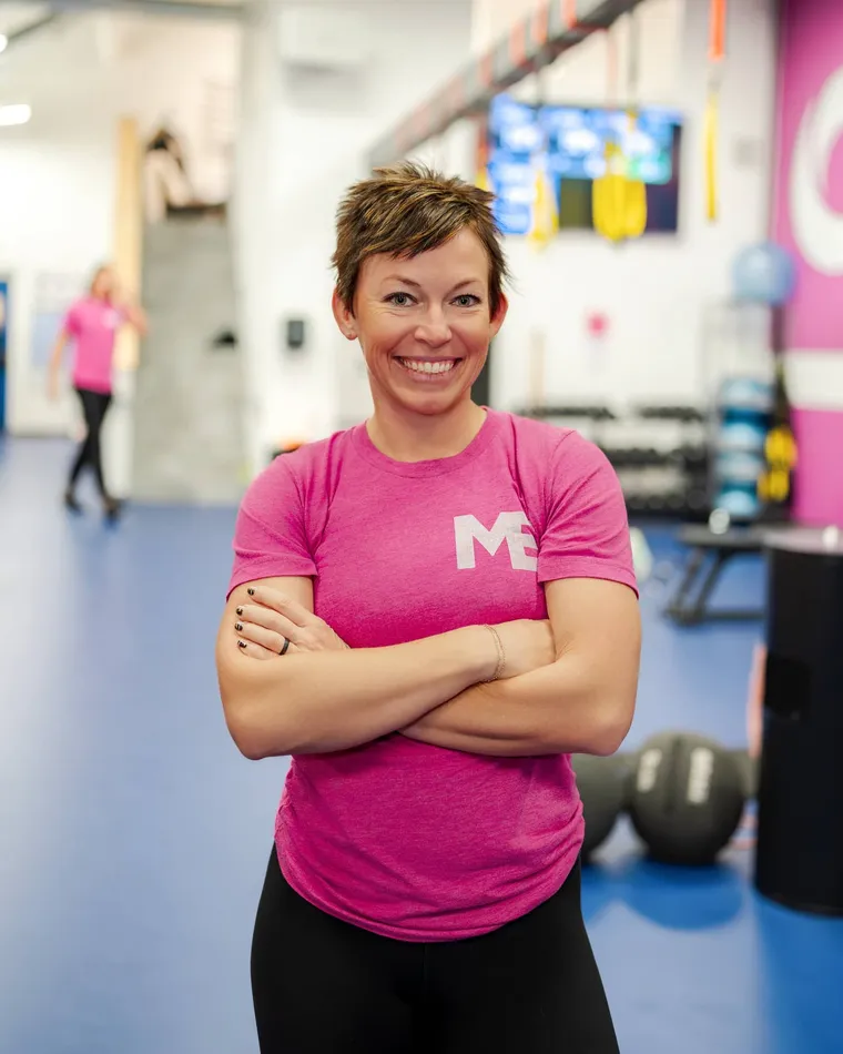 Megan Cooper, owner and head coach of Studio ME Fitness, standing with arms crossed and smiling in the Northeast Minneapolis studio.