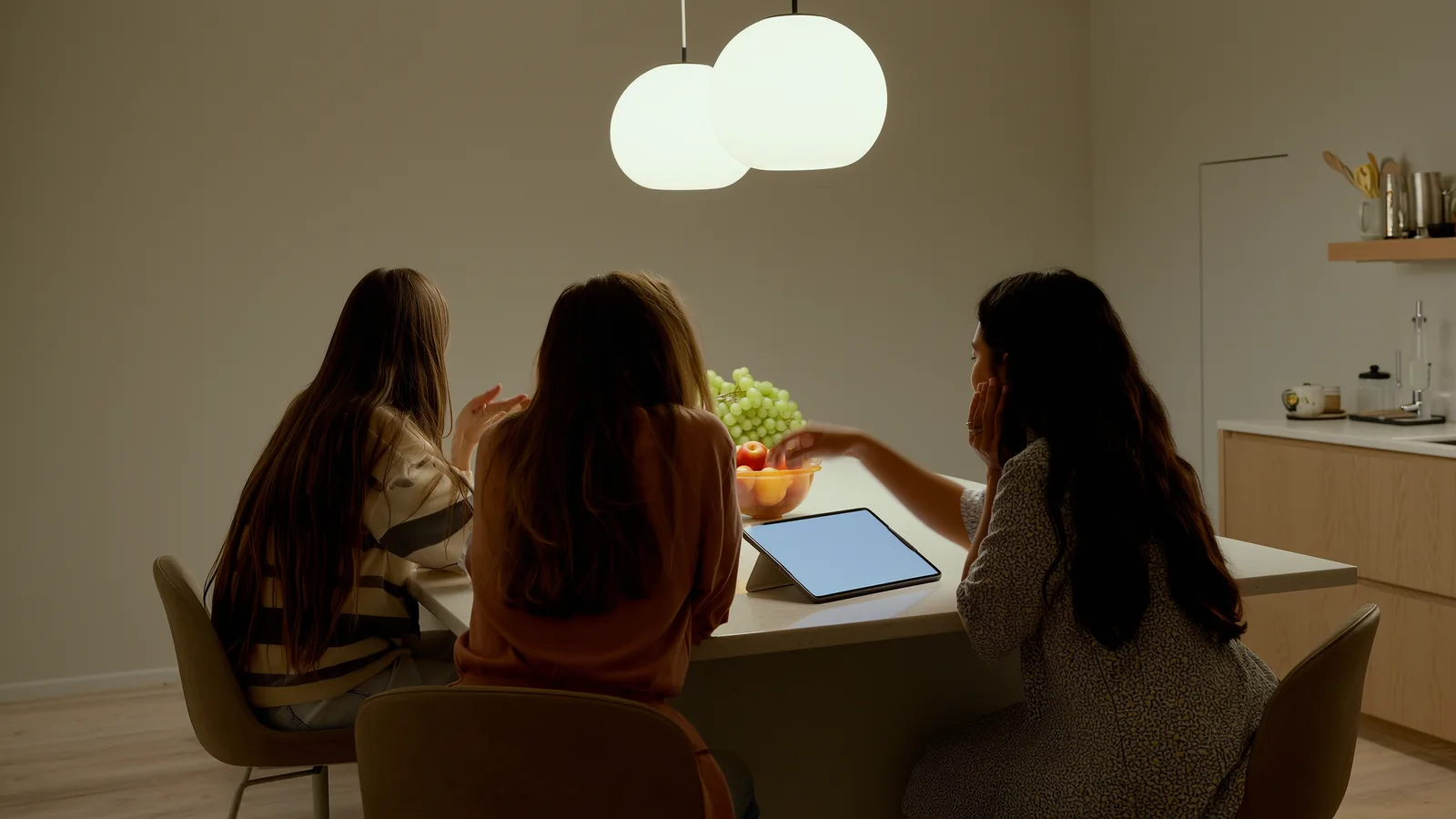 Three people around a kitchen island with a tablet propped up between them